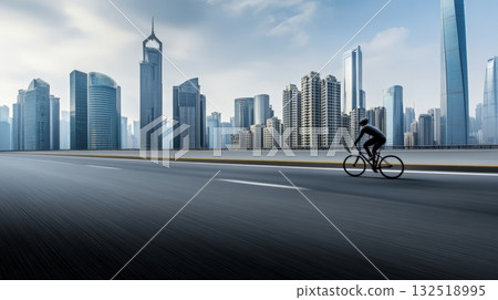 Professional cyclist riding a bicycle on an empty highway with modern city skyline in the background, showcasing urban transportation and healthy lifestyle 132518995