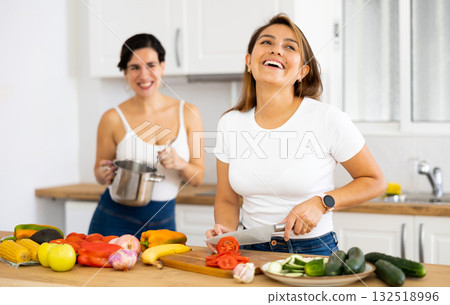 Two cheerful female friends preparing salad and soup together in kitchen Two cheerful female friends preparing salad and soup together in kitchen 132518996