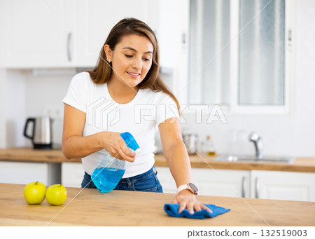 Woman cleaning kitchen countertop with cleaning spray and rag Woman cleaning kitchen countertop with cleaning spray and rag 132519003