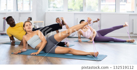 Girl exercising with figure eight resistance band in pilates class Girl exercising with figure eight resistance band in pilates class 132519112