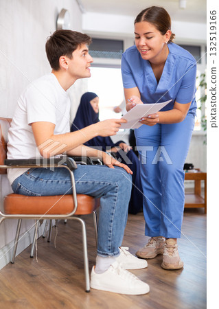 Young woman medic gives document to teenager boy for signing Young woman medic gives document to teenager boy for signing 132519166