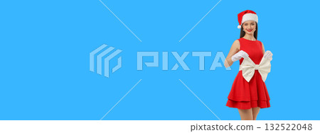 Woman in red dress and Santa hat holds big white bow 132522048