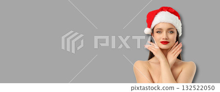 Woman adorned in a Santa hat poses with a cheerful expression 132522050