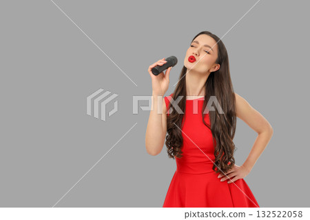Singer with long hair wearing a red dress holds a microphone Singer with long hair wearing a red dress holds a microphone 132522058