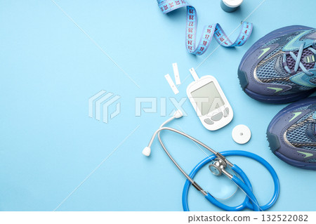 Diabetes monitoring tools and sports shoes on blue surface Diabetes monitoring tools and sports shoes on blue surface 132522082
