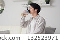 Asian man drinking protein in the living room 132523971