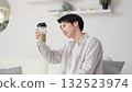 Asian man looking at protein shake in living room 132523974