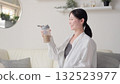 Asian woman looking at protein shake in living room 132523977