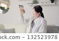 Asian woman looking at protein shake in living room 132523978