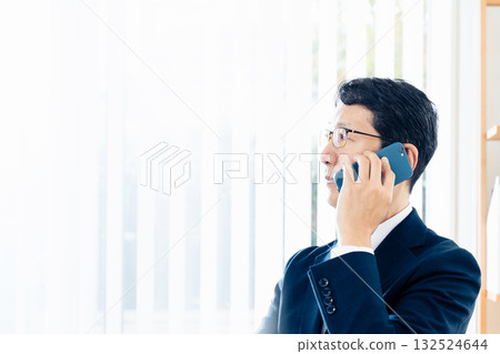 A middle-aged businessman talking on a smartphone A middle-aged businessman talking on a smartphone 132524644