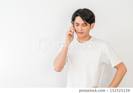 Young Asian man talking on smartphone (troubled, trouble, stress, anxiety) Young Asian man talking on smartphone (troubled, trouble, stress, anxiety) 132525139