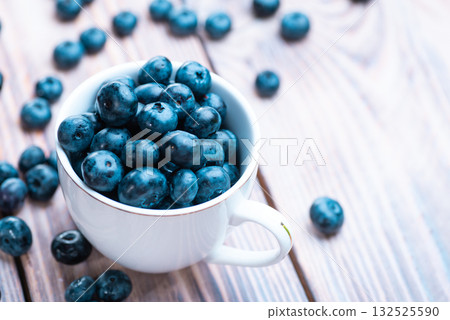 Fresh blueberries in a white cup on a wooden table 132525590