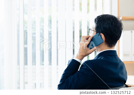 A middle-aged businessman talking on a smartphone A middle-aged businessman talking on a smartphone 132525712