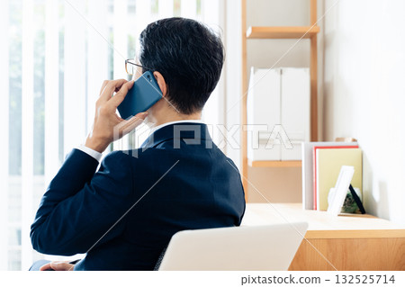 A middle-aged businessman talking on a smartphone A middle-aged businessman talking on a smartphone 132525714