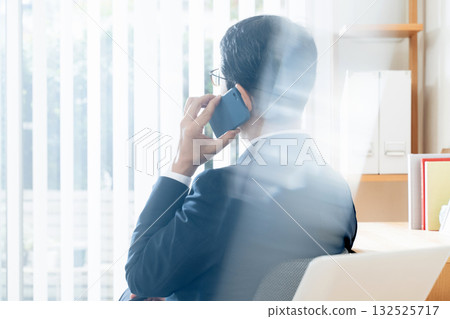 A middle-aged businessman talking on a smartphone A middle-aged businessman talking on a smartphone 132525717