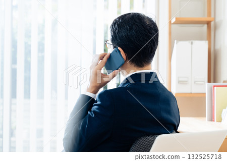 A middle-aged businessman talking on a smartphone A middle-aged businessman talking on a smartphone 132525718