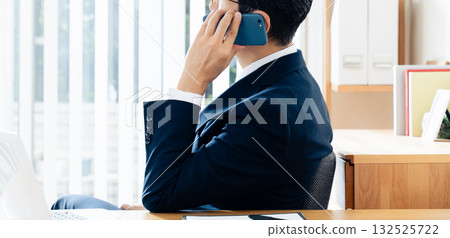 A middle-aged businessman talking on a smartphone A middle-aged businessman talking on a smartphone 132525722