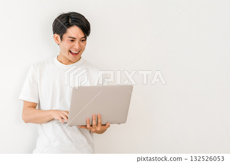 A young Asian man in a T-shirt holding a laptop (freelance, creator, programmer) 132526053