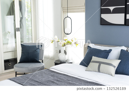 Stylish Bedroom in blue and white tone pillows setting. Cozy bedroom with art wall. Stylish Bedroom in blue and white tone pillows setting. Cozy bedroom with art wall. 132526189