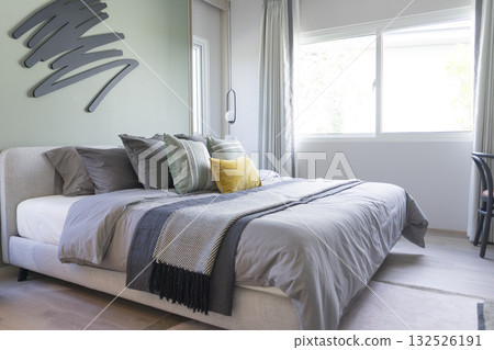 Stylish Bedroom in blue and white tone pillows setting. Cozy bedroom with art wall. 132526191