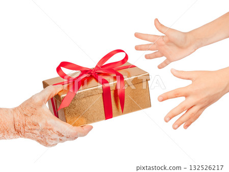 Elderly hand offering a golden gift box with red ribbon to younger hands reaching out, isolated. Symbol of giving, love, care, hope, connection between generations for holiday, family concepts 132526217