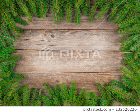 Christmas background with green fir branches forming a natural frame on rustic wooden table, top view, copy space for text or holiday design Christmas background with green fir branches forming a natural frame on rustic wooden table, top view, copy space for text or holiday design 132526220