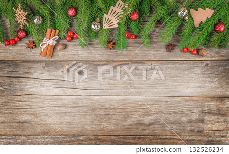 Christmas background with fir branches, red berries, wooden ornaments, cinnamon sticks, and anise on rustic wooden surface, top view with copy space for festive design or greeting card Christmas background with fir branches, red berries, wooden ornaments, cinnamon sticks, and anise on rustic wooden surface, top view with copy space for festive design or greeting card 132526234