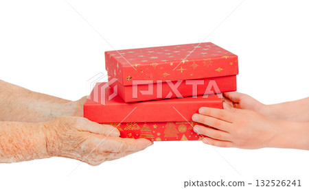 Elderly and young hands exchanging red gift boxes with golden decoration, isolated on white background. Symbolic image of giving, care, family connection, and Christmas generosity between generations Elderly and young hands exchanging red gift boxes with golden decoration, isolated on white background. Symbolic image of giving, care, family connection, and Christmas generosity between generations 132526241