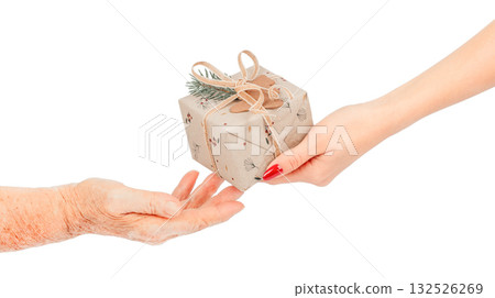 Close-up of young female hands giving a small eco-friendly gift wrapped. pine twig to elderly hands concept of kindness, care intergenerational connection, isolated on white Close-up of young female hands giving a small eco-friendly gift wrapped. pine twig to elderly hands concept of kindness, care intergenerational connection, isolated on white 132526269