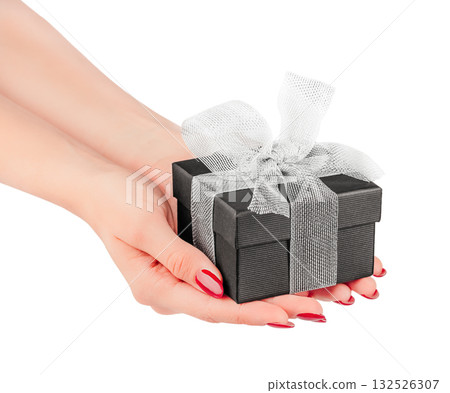 Female hands holding small black gift box with silver ribbon bow isolated on white background elegant minimal concept for luxury present, Christmas, birthday romantic celebration design 132526307