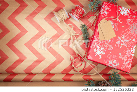 Festive red Christmas gift wrapping with snowflake pattern, twine, tags, and craft paper on rustic background with copy space 132526328