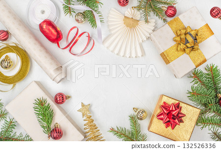 Festive Christmas flat lay with gift boxes, golden and red ribbons, baubles, fir branches, and paper angel decoration on white background with copy space holiday celebration concept Festive Christmas flat lay with gift boxes, golden and red ribbons, baubles, fir branches, and paper angel decoration on white background with copy space holiday celebration concept 132526336