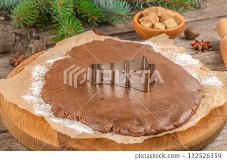 Christmas baking concept with gingerbread dough and a metal cookie cutter in the shape of a tree on a rustic wooden background Christmas baking concept with gingerbread dough and a metal cookie cutter in the shape of a tree on a rustic wooden background 132526359