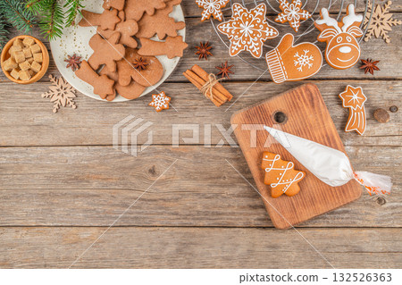Christmas cookie decorating concept with festive gingerbread, icing bag, and holiday elements on a rustic wooden background. copy space. top view 132526363