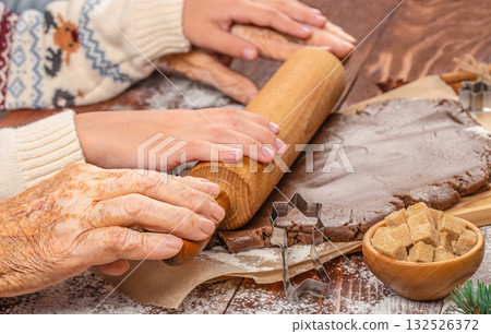 Generational hands working together to roll gingerbread dough, symbolizing family connection, tradition, and shared holiday baking moments Generational hands working together to roll gingerbread dough, symbolizing family connection, tradition, and shared holiday baking moments 132526372