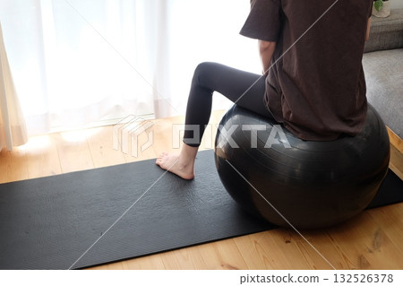 Back view of a woman riding a balance ball Back view of a woman riding a balance ball 132526378