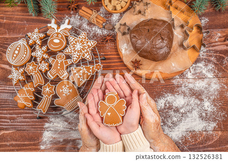 Generational family bonding and holiday baking concept with elderly and young hands holding a gingerbread angel cookie together, symbolizing love, care, tradition, and Christmas spirit Generational family bonding and holiday baking concept with elderly and young hands holding a gingerbread angel cookie together, symbolizing love, care, tradition, and Christmas spirit 132526381