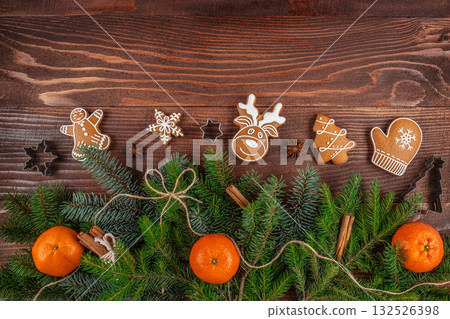Festive Christmas composition with gingerbread cookies, fir branches, tangerines, and spices on a wooden background, perfect for holiday design and seasonal advertising Festive Christmas composition with gingerbread cookies, fir branches, tangerines, and spices on a wooden background, perfect for holiday design and seasonal advertising 132526398