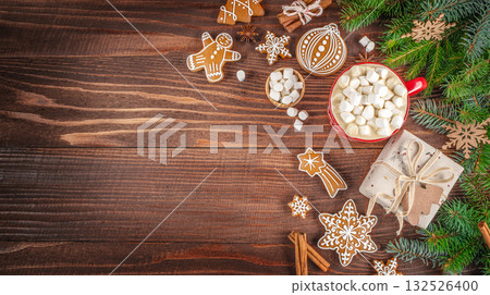 Festive Christmas composition with hot cocoa and marshmallows, gingerbread cookies, gift box, and fir branches on a rustic wooden background. copy space. top view Festive Christmas composition with hot cocoa and marshmallows, gingerbread cookies, gift box, and fir branches on a rustic wooden background. copy space. top view 132526400
