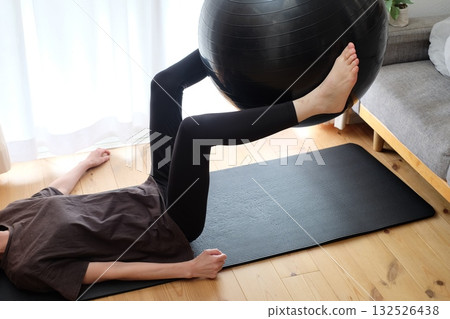 A woman exercising with a balance ball 132526438