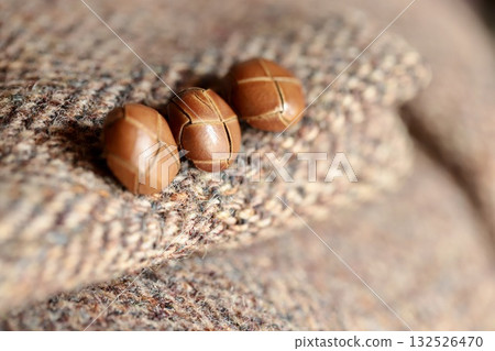Leather buttons on the cuffs of a tweed jacket 132526470