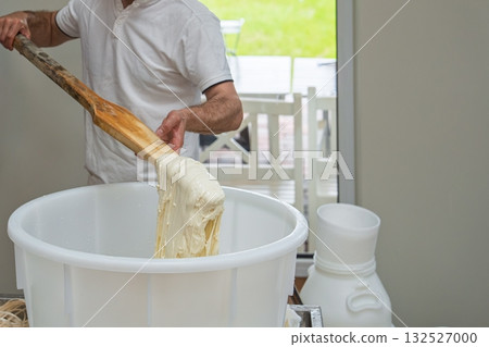 Artisan Pasta Maker Carefully Mixes Dough in Large Tub with Wooden Paddle for Authentic Texture 132527000