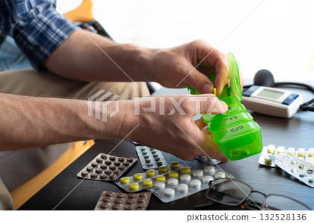 Middle aged caucasian man distributing scheduled dose of medication in dosette box 132528136