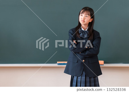 Elementary school, junior high school, and high school girls in uniforms with angry expressions and arms crossed in front of the classroom blackboard 132528336