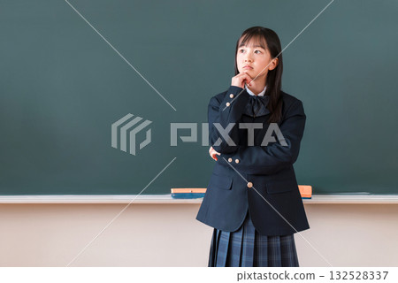 Elementary school, junior high school, and high school girls in uniforms thinking and worrying in front of the blackboard in the classroom 132528337