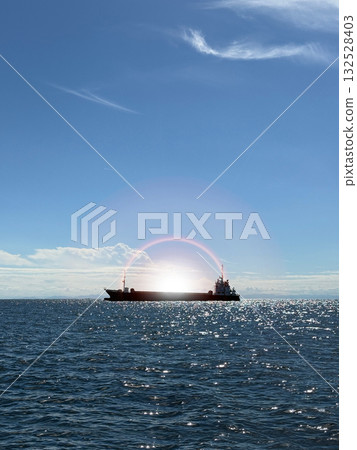 一艘貨船漂浮在海面上,夕陽的餘暉在海面上投下斑駁的光影。 一艘貨船漂浮在海面上,夕陽的餘暉在海面上投下斑駁的光影。 132528403