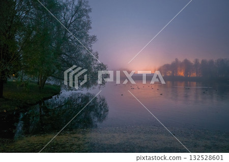 Photo twilight view of the lake with a glow of fire on the horizon. 132528601