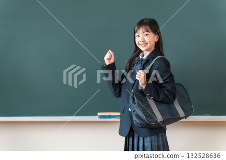 Female elementary, junior high, and high school students in blazers standing in front of the blackboard and making a fist pump Female elementary, junior high, and high school students in blazers standing in front of the blackboard and making a fist pump 132528636
