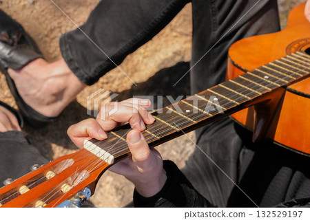 Close up hands of playing string guitar outdoors in autumn forest. Concept of sound therapy, mental health and wellness rituals. Calmness tranquility audio-sensory practices. Aura farming energy 132529197