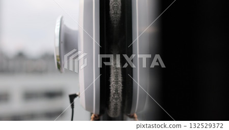 Close up automatic window cleaning robot operating on residential window. Simplicity and convenience of window cleaning. Close up automatic window cleaning robot operating on residential window. Simplicity and convenience of window cleaning. 132529372